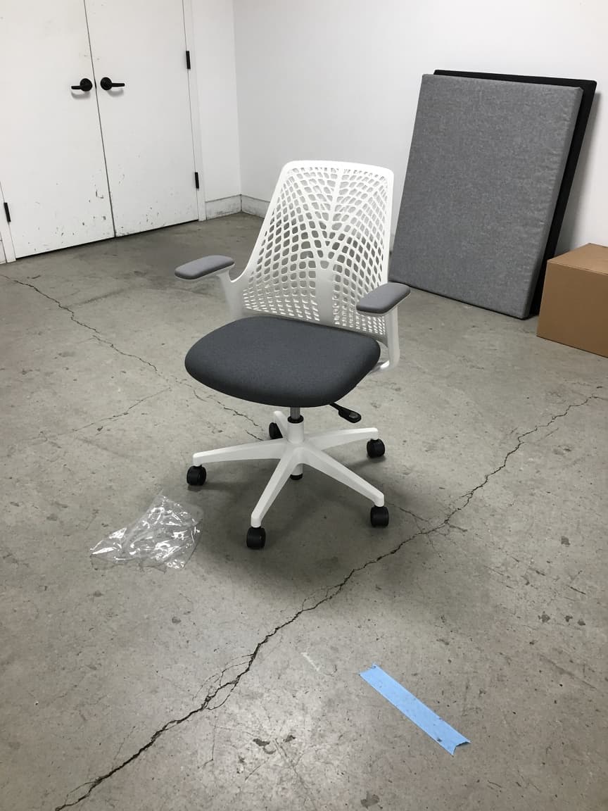 Herman Miller Sayl, white frame and charcoal seat, photographed on the warehouse floor